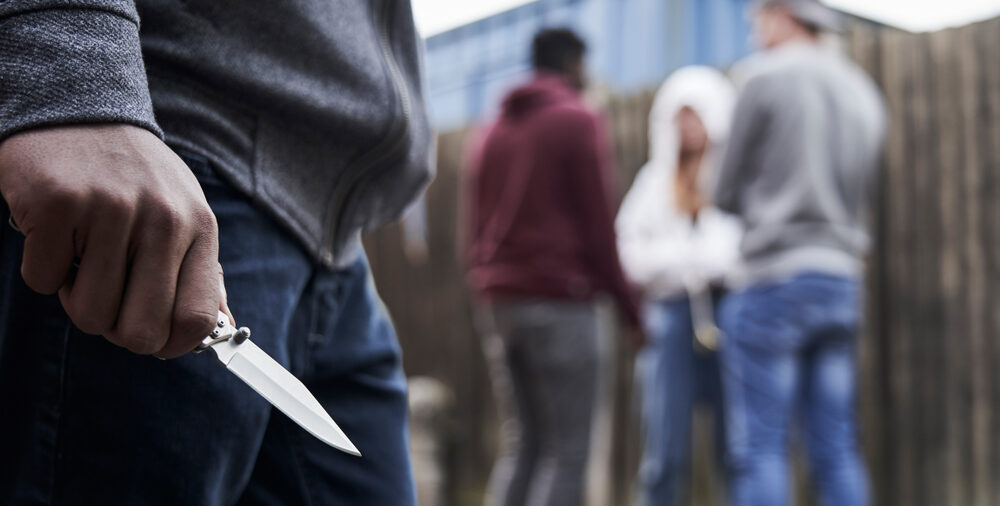 Jongen houdt mes vast met op de achtergrond een aantal andere jongeren